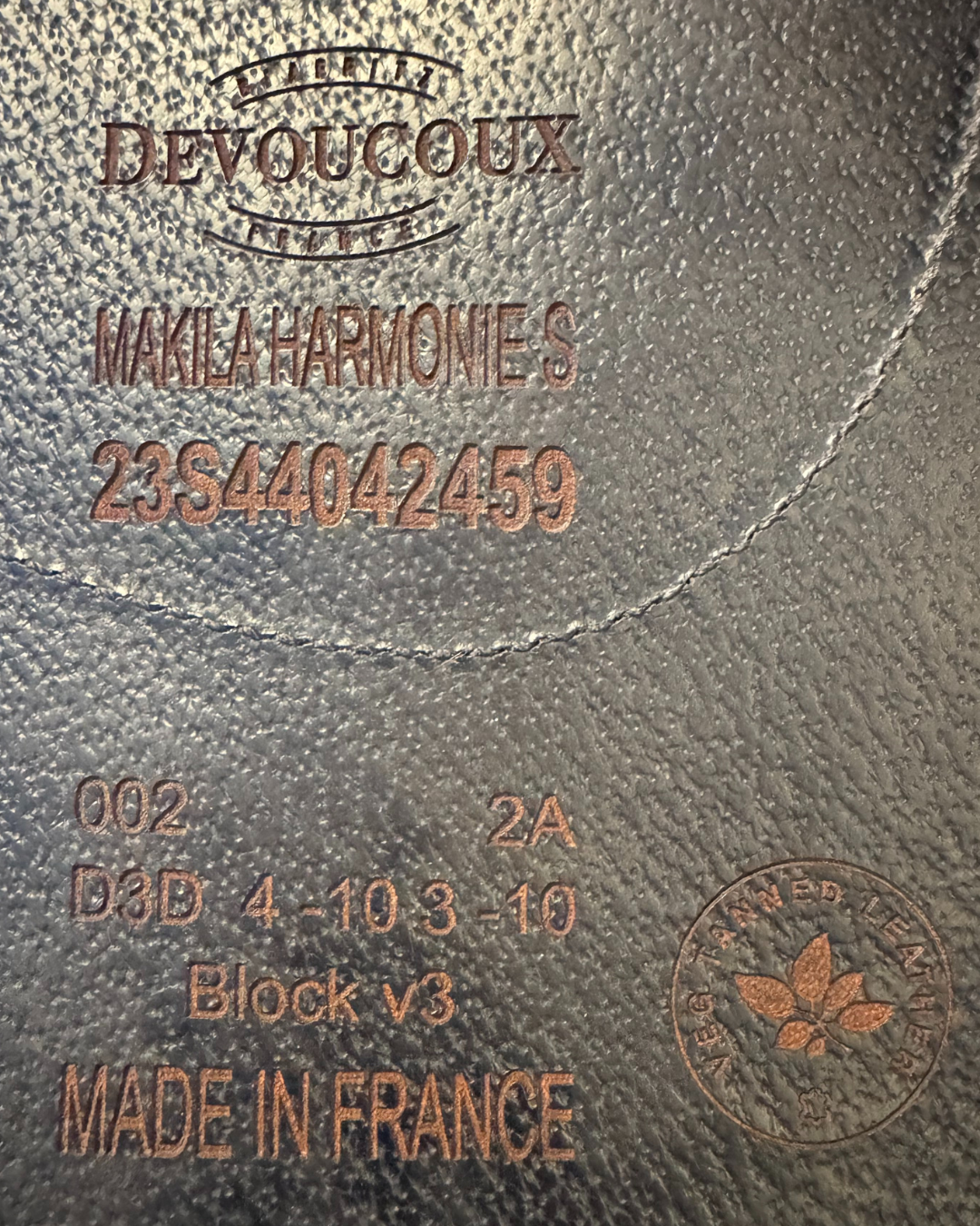 Close-up of a leather product with branding and text, including 'Devoucoux' and 'Made in France'.