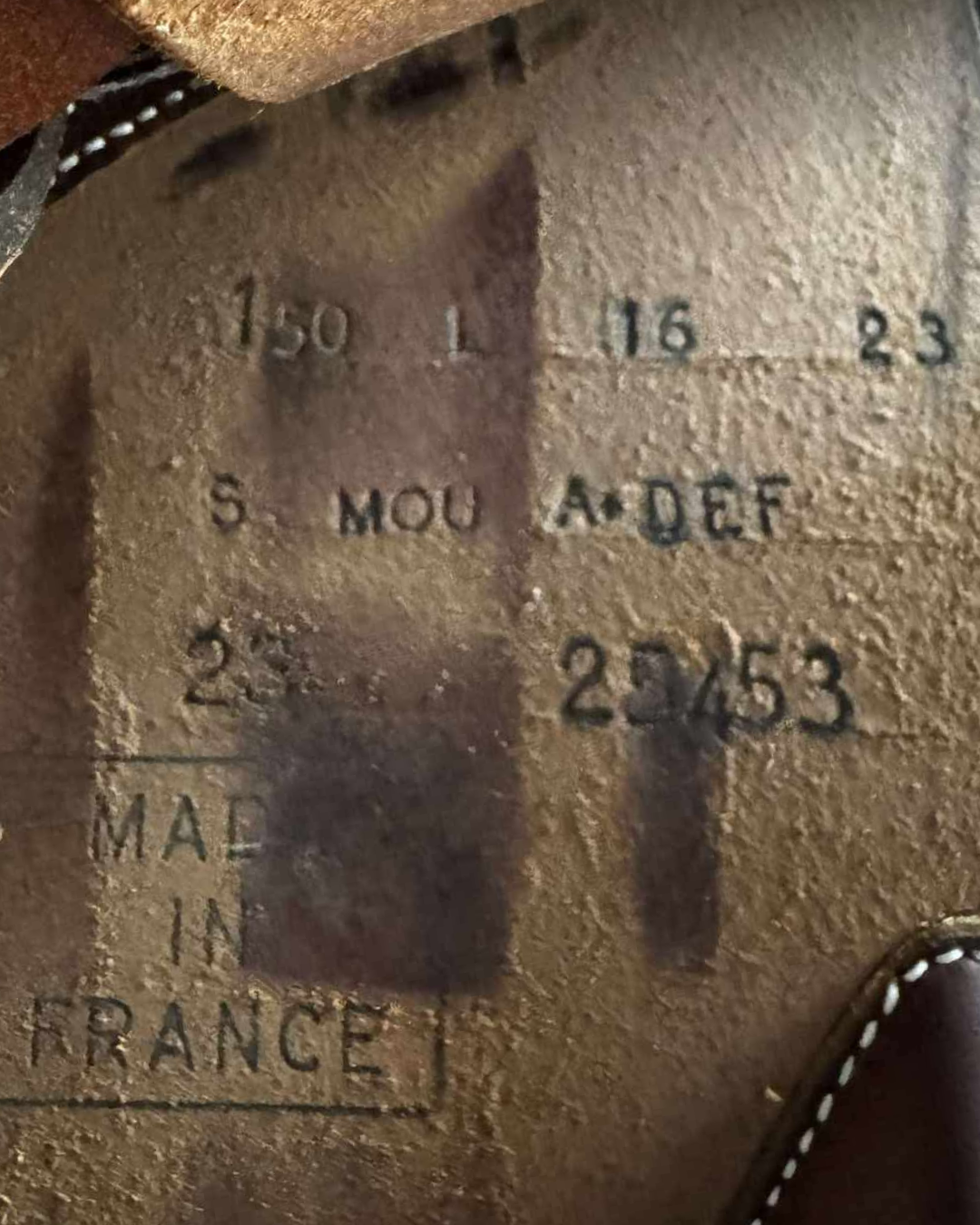 Close-up of a leather product with embossed text and 'Made in France' stamp.